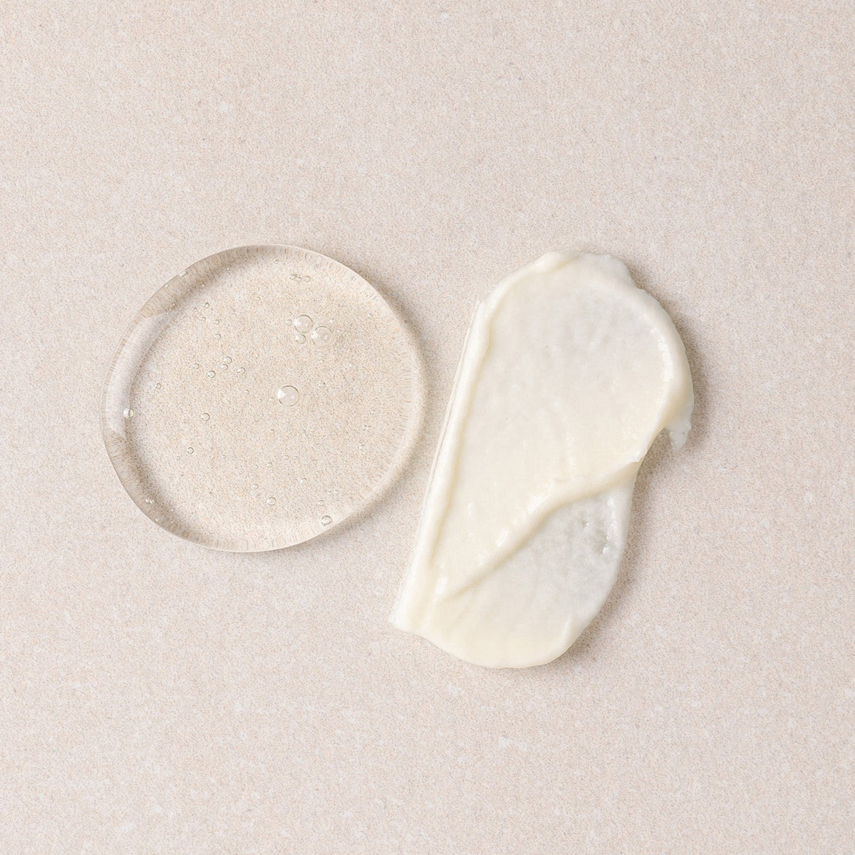 Two droplets of white cream on a beige background
