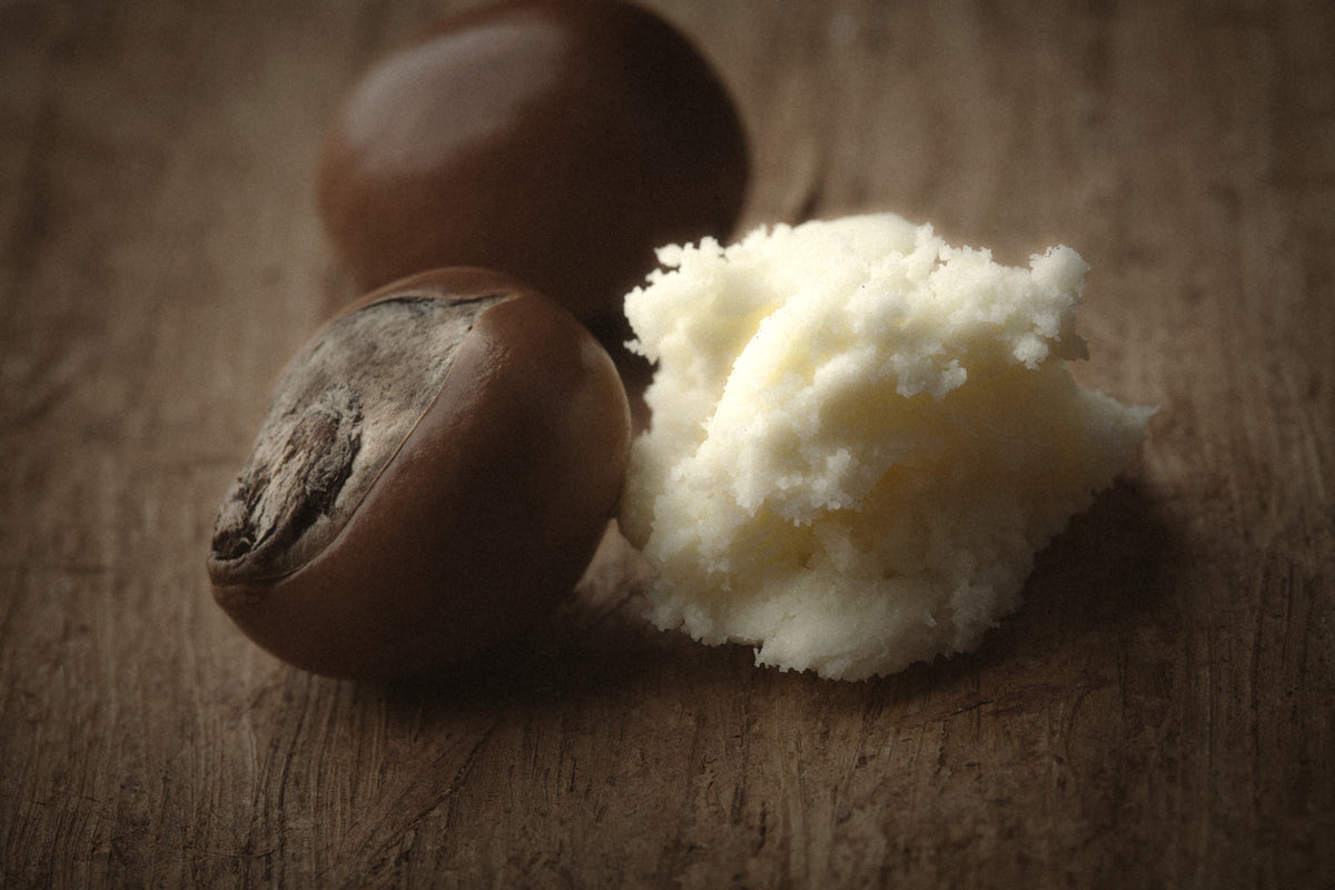 Two brown oval cosmetic or skincare capsules next to a small mound of off-white cream or balm on a rustic wooden surface.